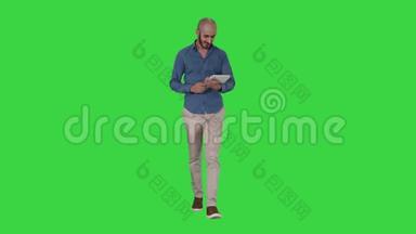 阿拉伯男人在<strong>绿色</strong>屏幕上行走和使用平板电脑<strong>上网</strong>，Chroma键。
